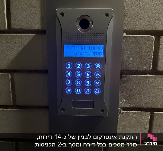 אינטרקום עם מקלדת מוארת בכחול על קיר לבנים